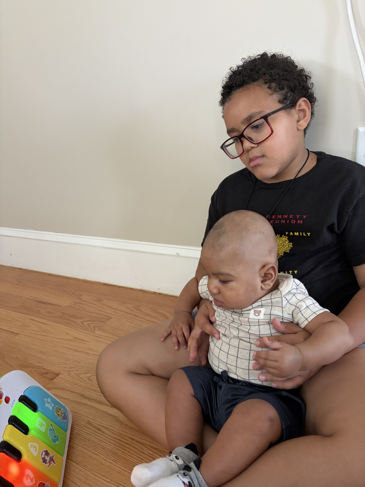 Prince holding a baby beside a toy piano